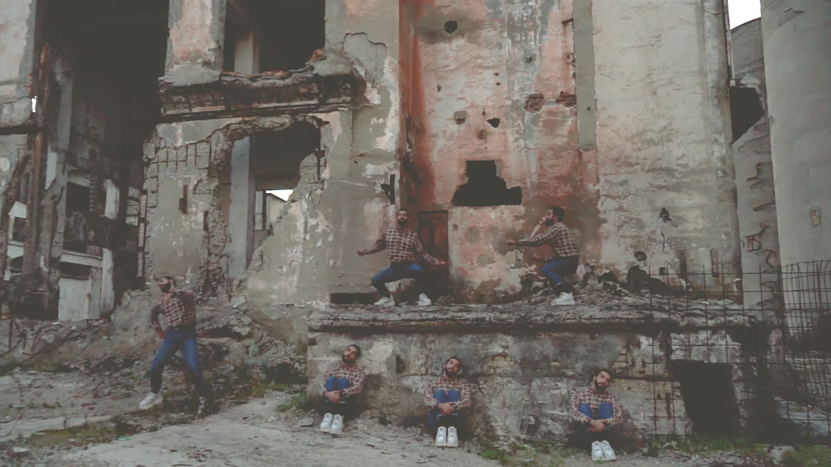 Pose diverse fra le macerie: chi cammina, chi siede, chi si arrampica sul muro rosa scrostato
