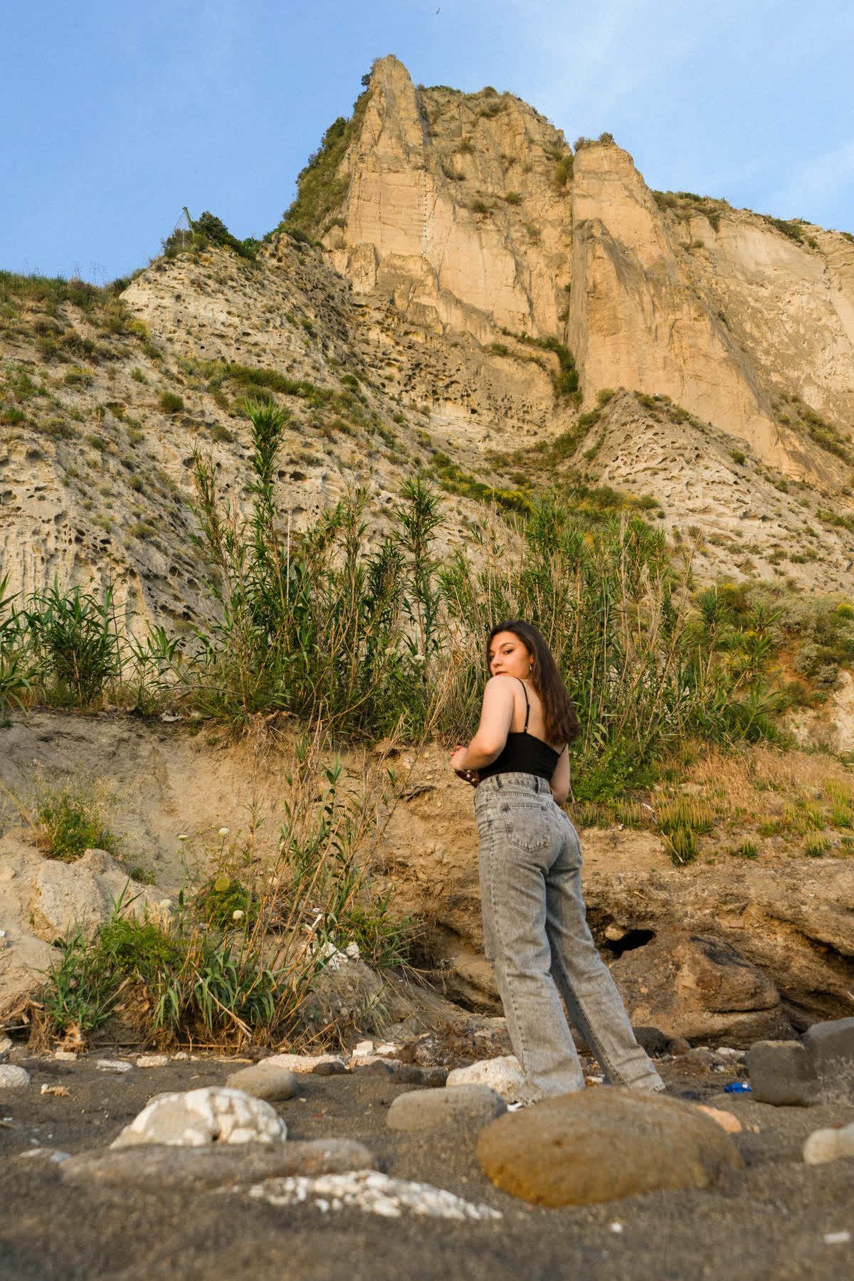 In spiaggia al tramonto, di spalle verso il faraglione, fra le canne